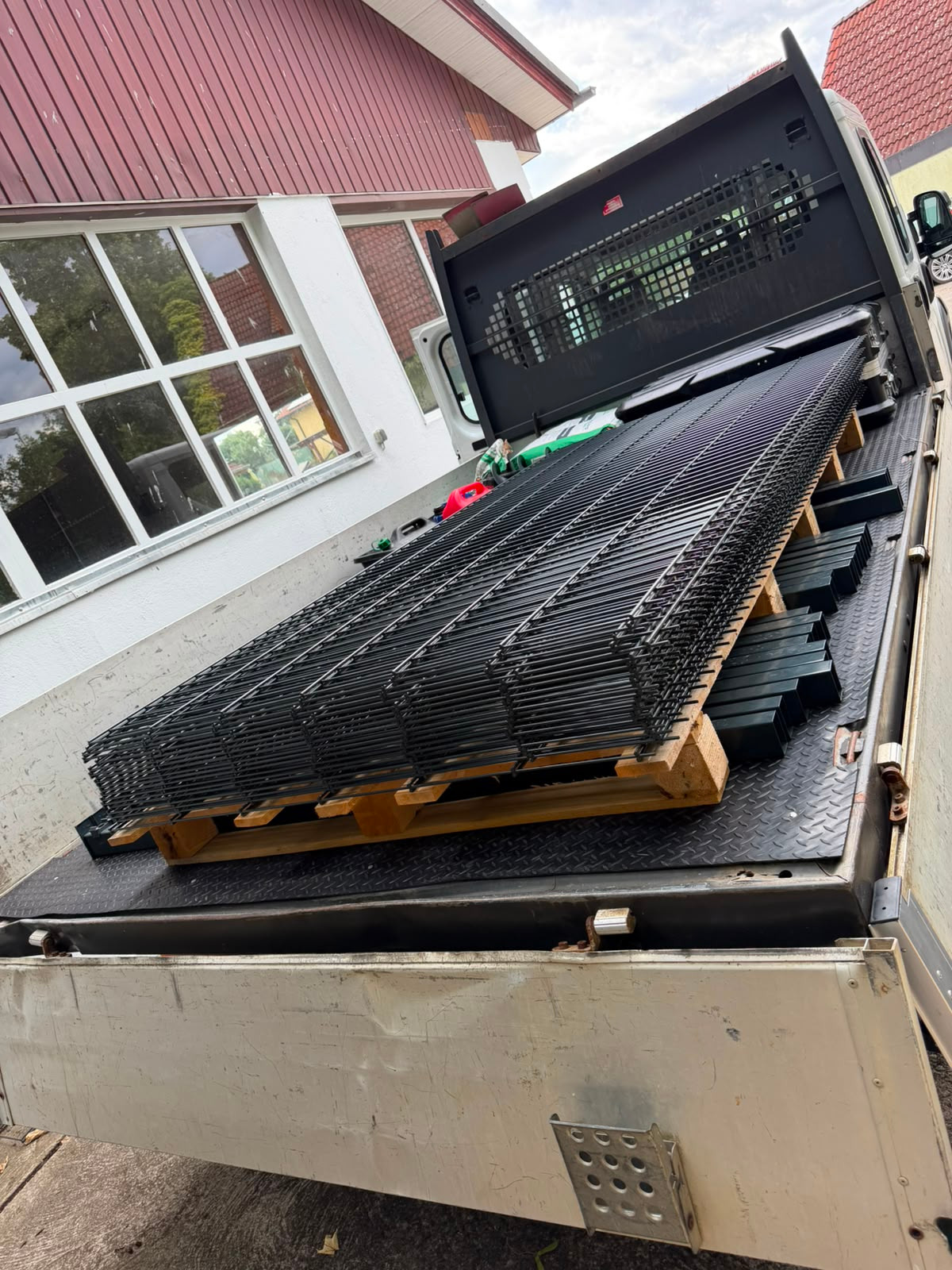 Eckanlage mit passendem Gartentor, Übergang von Pflasterfläche zu Kiesbereich – abgestimmte Pfostenoptik.