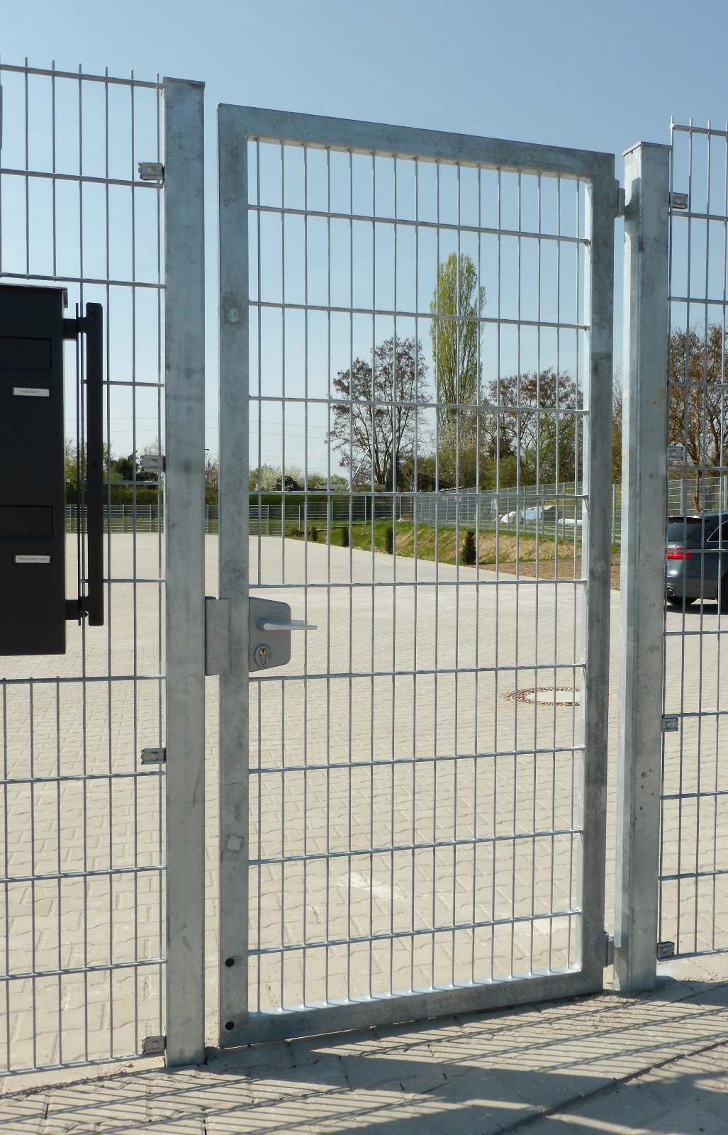 Einfahrtstor mit Schmuckmatten-Bogen als repräsentativer Auftakt zur Grundstückszufahrt.