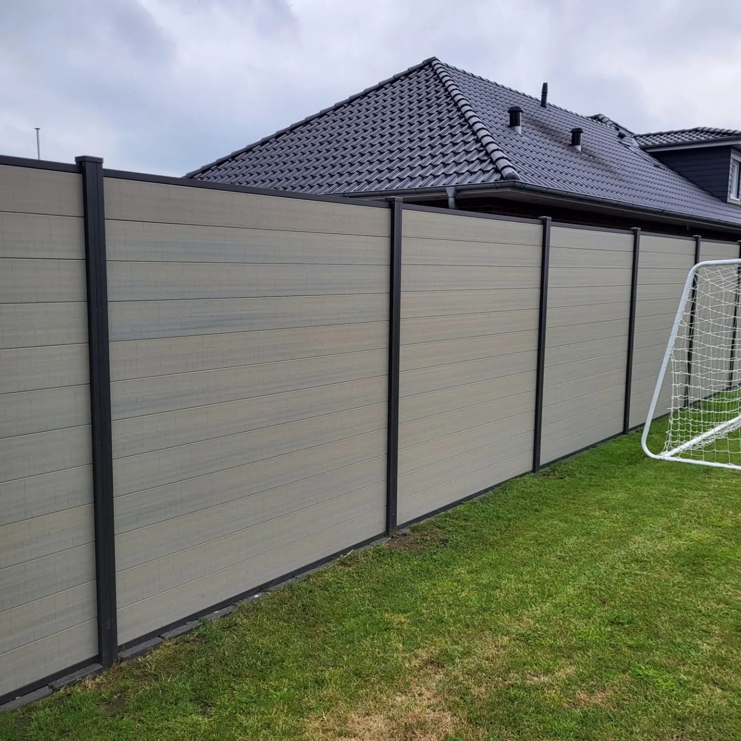 Moderner WPC-Sichtschutzzaun in Anthrazit mit horizontalen Holzoptik-Profilen entlang einer Terrasse.