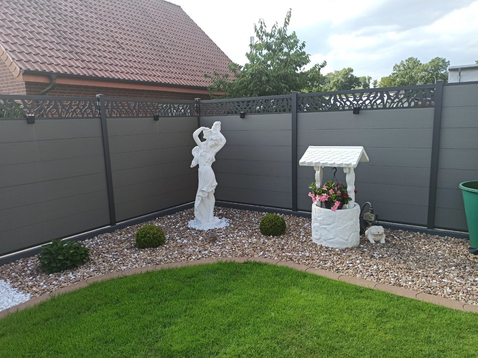WPC-Zaun in warmem Holzton als blickdichte Grundstücksgrenze im modernen Garten.